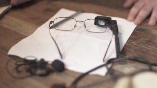 photo of live time closed captioning system - pair of glasses with an attached camera resting on a table