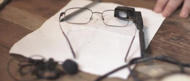 photo of live time closed captioning system - pair of glasses with an attached camera resting on a table