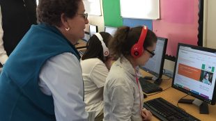 A teacher looking at a student who is using bookshare in audio format