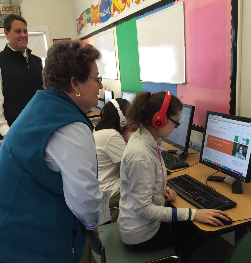 A teacher looking at a student who is using bookshare in audio format