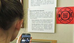 a person scanning a qr code displayed on the wall with their phone to watch the exhibit's ASL video tour