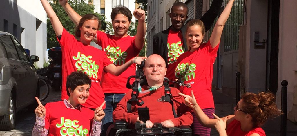 a group of people smiling. There is a person in the middle in a wheelchair.