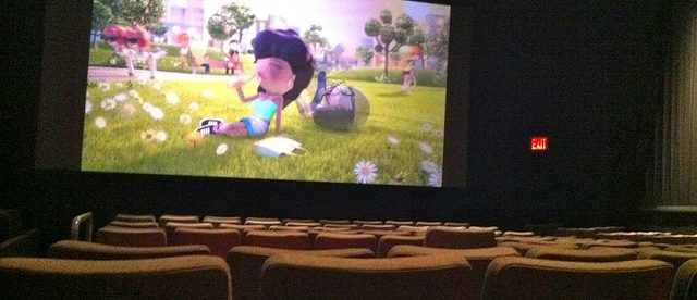 photo of a movie being shown at a movie theater. There are empty seats everywhere.