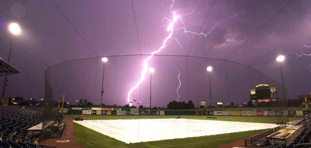 photo of a softball field with lightning in the background