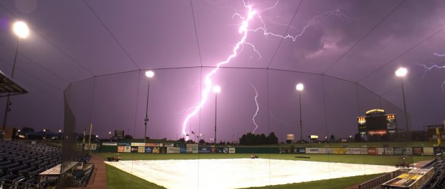 photo of a softball field with lightning in the background