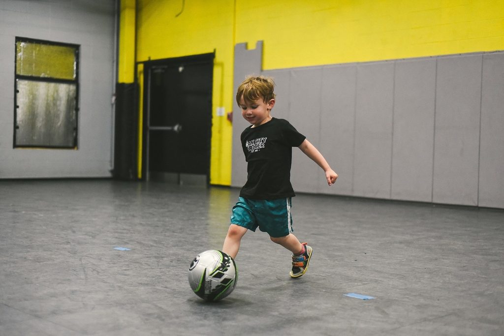 a little boy kicking a soccer ball at the oak city soccer venue