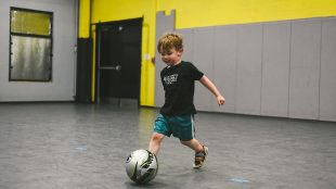 a little boy kicking a soccer ball at the oak city soccer venue