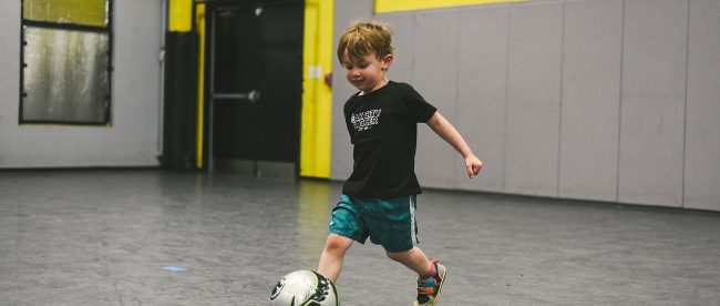 a little boy kicking a soccer ball at the oak city soccer venue