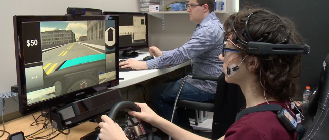 An adolescent hooked up to sensors and driving the virtual reality simulator