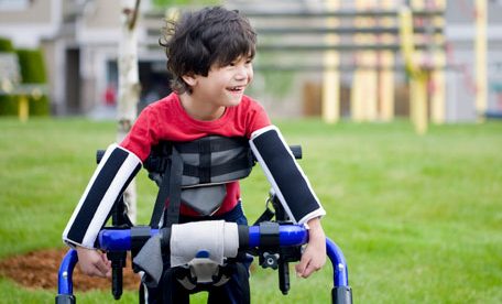 a young boy seen holding a crutches like support accessory and smiling