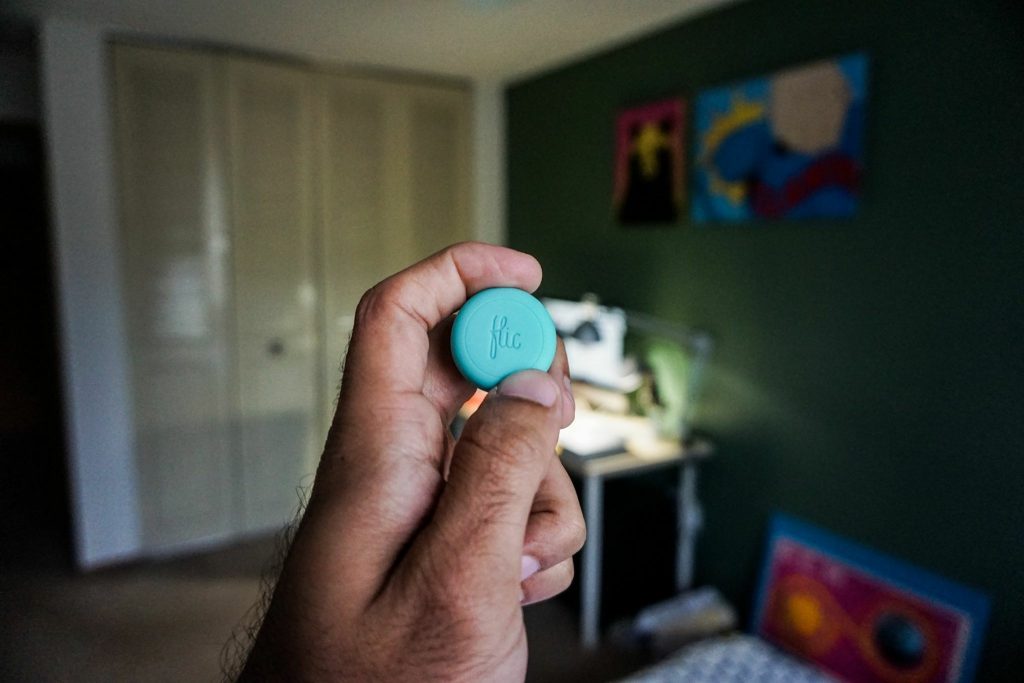 Close up of a person holding Flic - a small, round, smart wireless button.