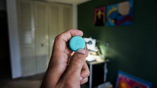 Close up of a person holding Flic - a small, round, smart wireless button.