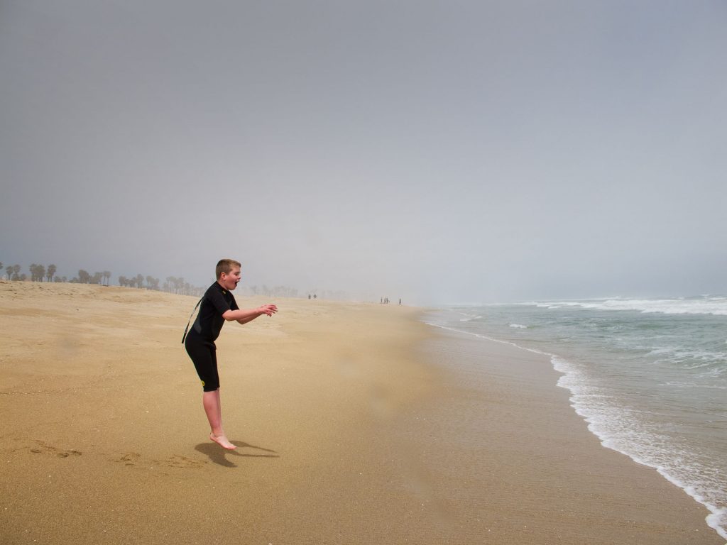 Bruce's son jumping at a beach.