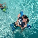 Bruce's sons playing in the swimming pool with another person.