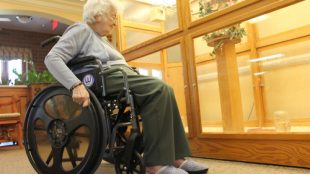 an elderly woman pushing a wheelchair that has Easy Push wheels installed.