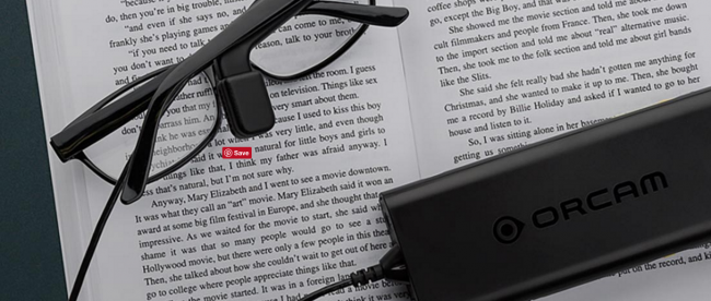 a pair of glasses with orcam myeye attached to the right stem resting on a book