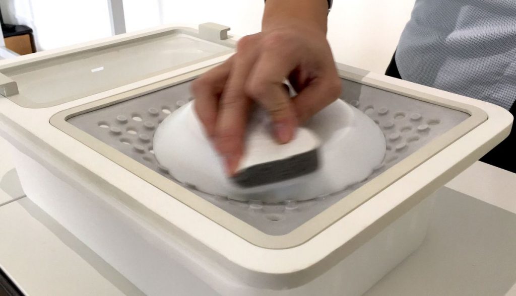 a person seen cleaning a dish with one hand. This dish is placed on the surface of the OneWare attachment used for cleaning dishes.