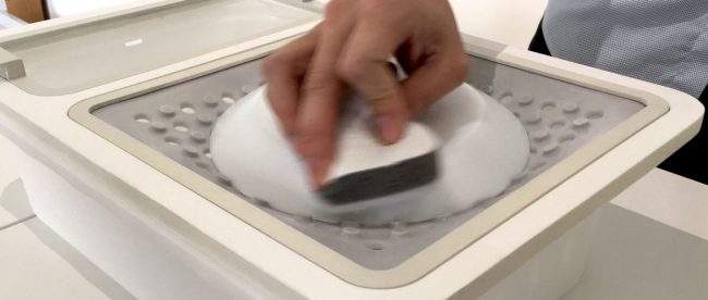 a person seen cleaning a dish with one hand. This dish is placed on the surface of the OneWare attachment used for cleaning dishes.