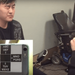Image shows a man winking at a phone held by another person right in front of him. At the bottom left is a close up of the back of the phone that this man is looking at. It has the sticker that has the layout similar to that of an e-train board.