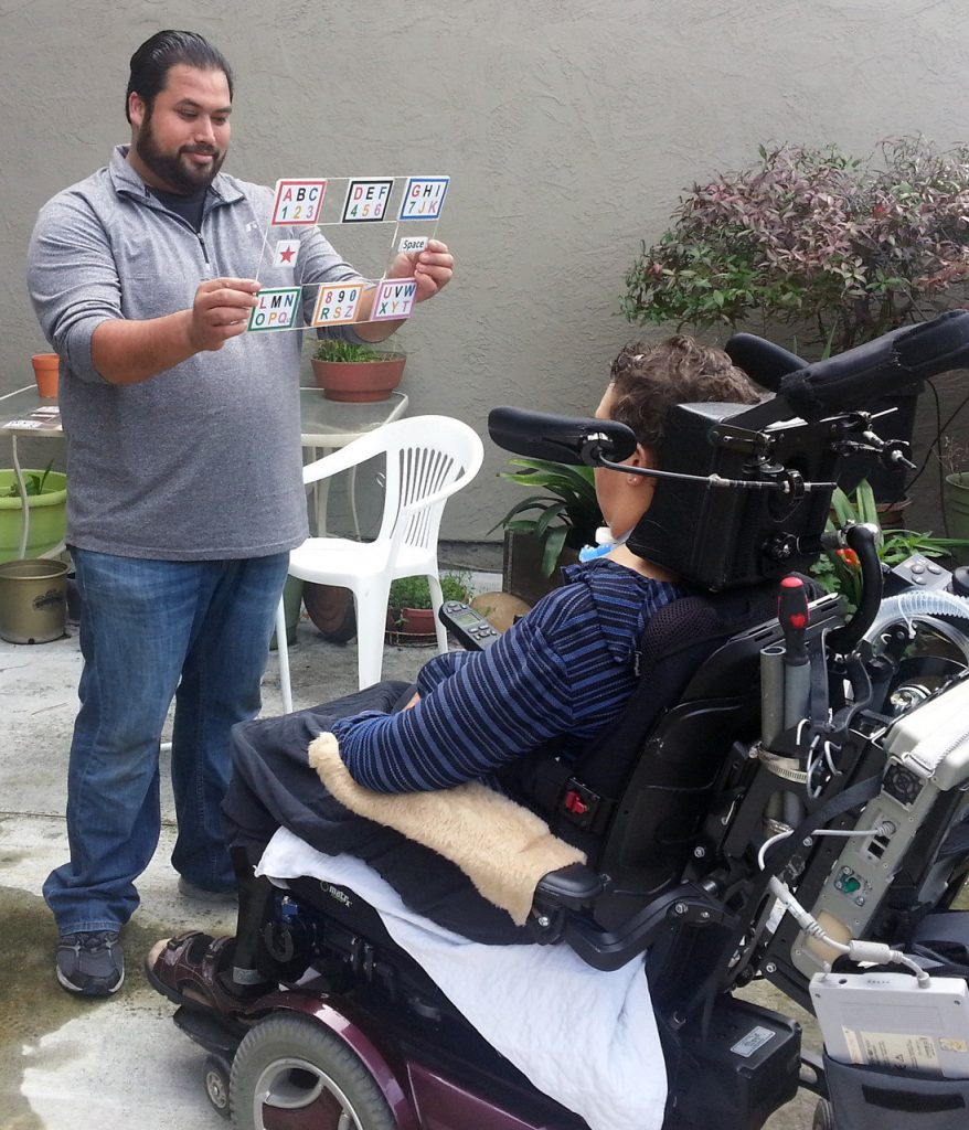 an interpreter displaying the e-tran board to a person in a wheelchair.