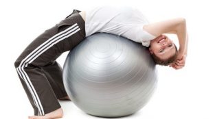 A young boy resting on an exercise ball