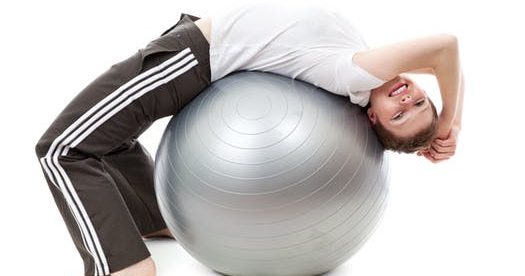 A young boy resting on an exercise ball