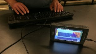 a keyboard is connected to a labquest 2, and the periodic table is displayed on the labquest 2's color screen. A person's hands are also placed on the keyboard.