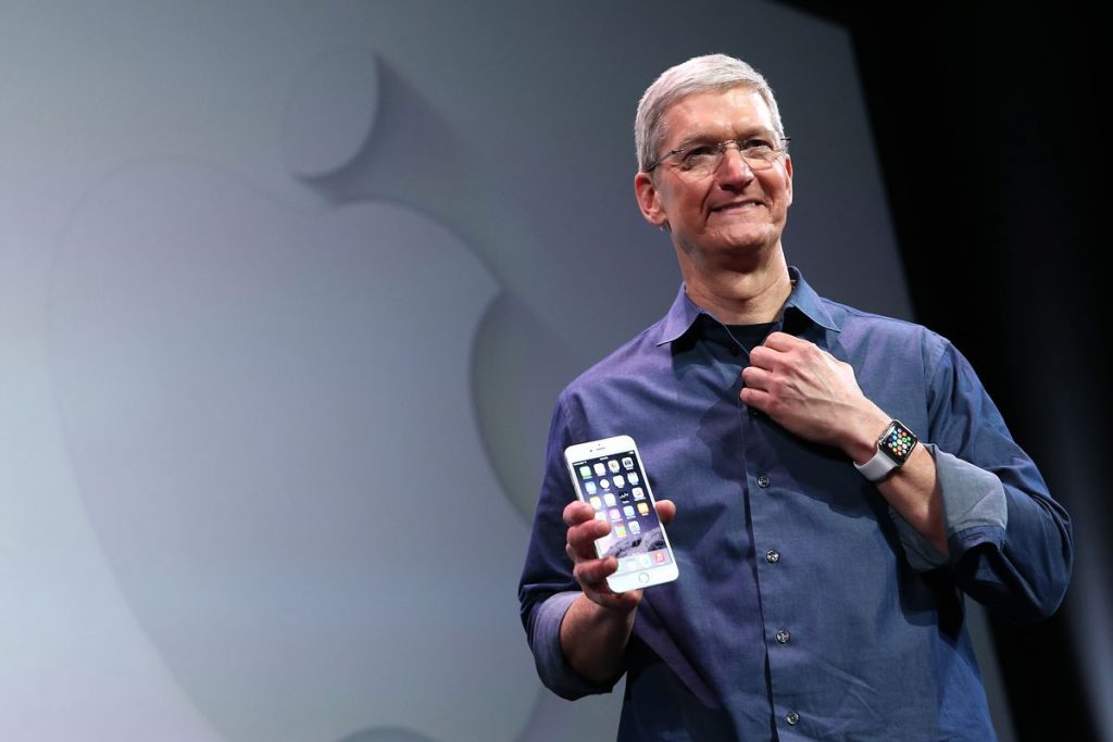 Tim Cook, CEO of Apple, seen holding an iphone in his right hand.