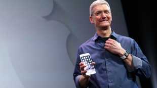 Tim Cook, CEO of Apple, seen holding an iphone in his right hand.