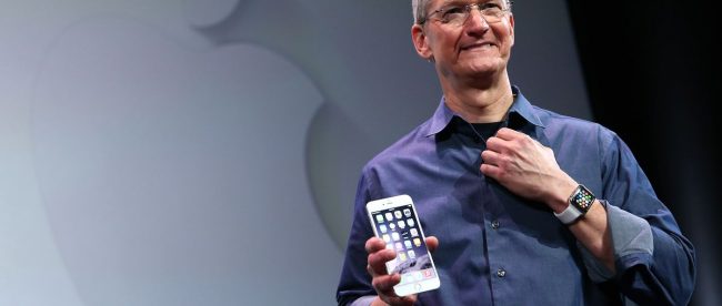 Tim Cook, CEO of Apple, seen holding an iphone in his right hand.