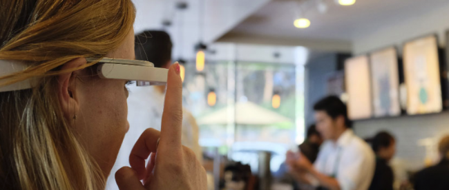 a woman in a coffees shop is seen pressing the button on her aira smartglasses.