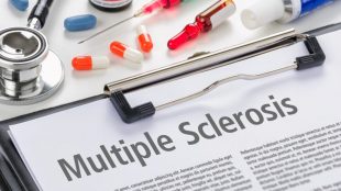 a clipboard with a sheet titled multiple sclerosis. A bunch of pills and a syringe are seen right next to it.