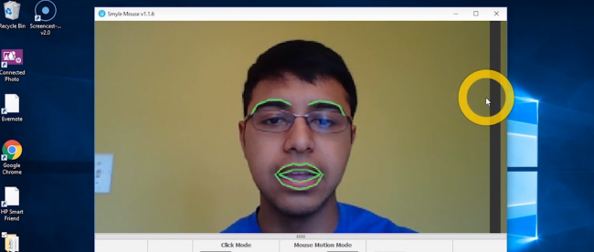 A user is seen using smyle mouse on a computer. The smyle mouse software highlights his eyebrows and lips in a separate window showing that it detects his facial expressions.