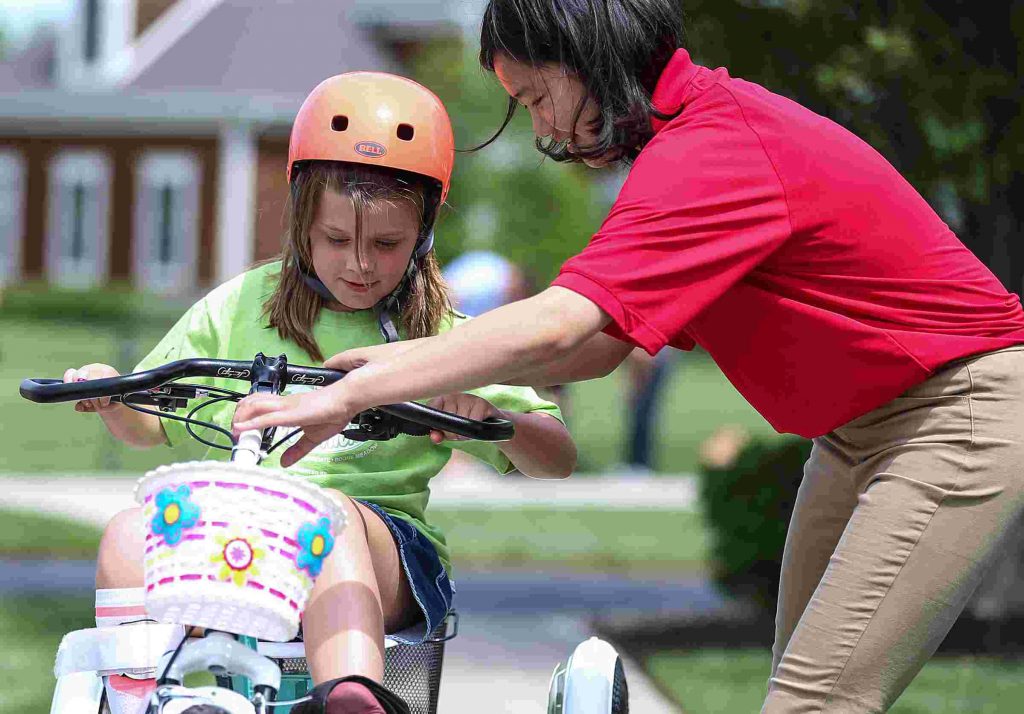 9 year old bella cates is seen on her bike. One of the students who designed the bike is seen adjusting her bike's handle bars.