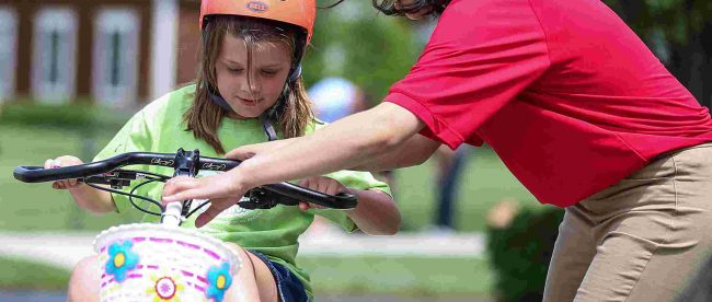 9 year old bella cates is seen on her bike. One of the students who designed the bike is seen adjusting her bike's handle bars.