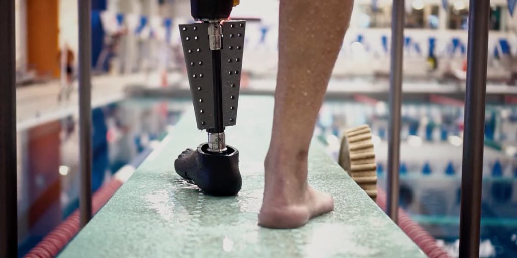 a person just about to get into a swimming pool seen wearing the fin prosthetic leg on his left side