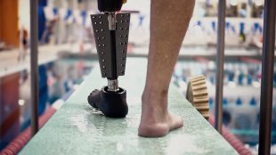 a person just about to get into a swimming pool seen wearing the fin prosthetic leg on his left side