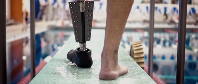 a person just about to get into a swimming pool seen wearing the fin prosthetic leg on his left side