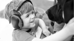 a young boy seen wearing headphones and playing with a dog