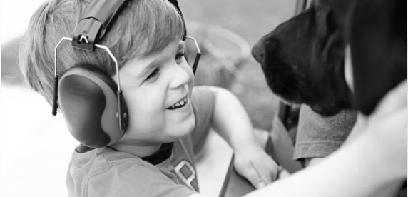 a young boy seen wearing headphones and playing with a dog