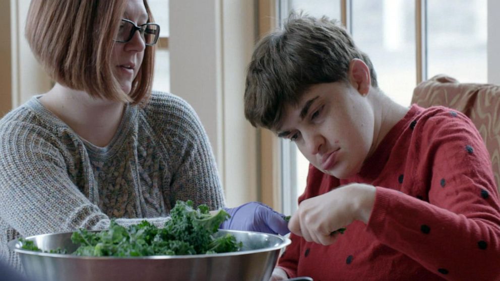 Two people seen with a bowl of what seems like kale or spinach