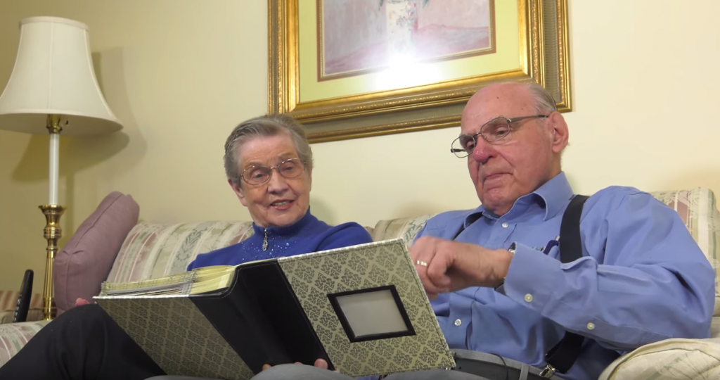 a woman who has alzheimer's sitting with her husband going through a photo album.