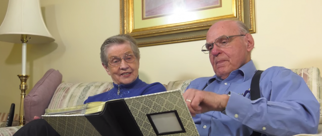 a woman who has alzheimer's sitting with her husband going through a photo album.