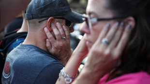 a man and a woman seen covering their ears with their hands.