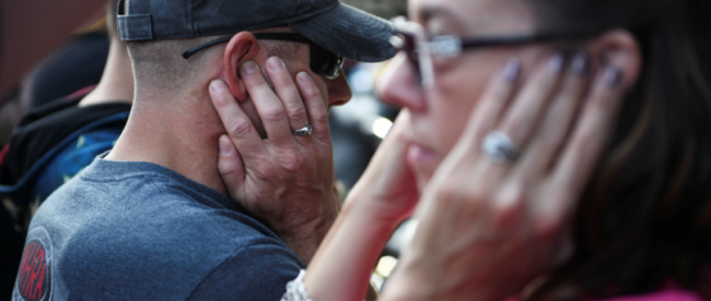 a man and a woman seen covering their ears with their hands.