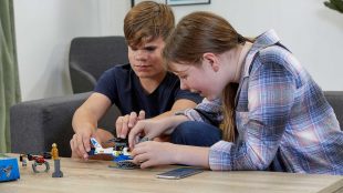 two blind teenagers building a lego set together.