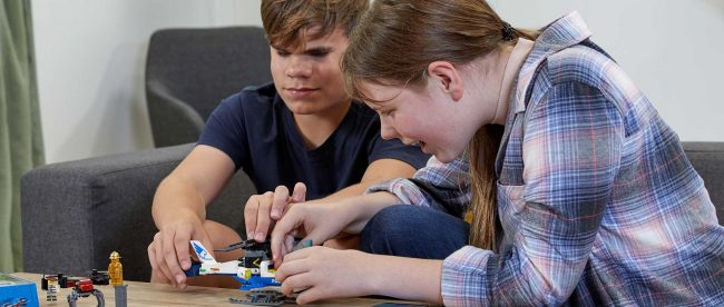 two blind teenagers building a lego set together.