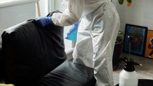 a person wearing PPE cleaning a couch