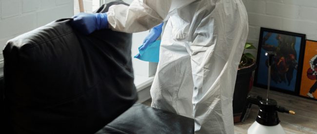 a person wearing PPE cleaning a couch