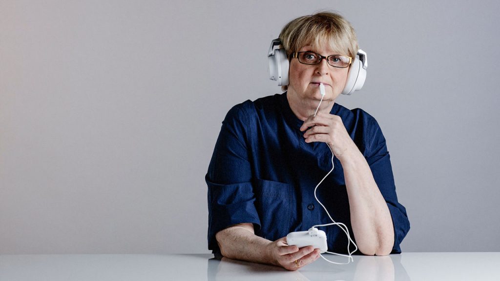 A person seen with the plastic paddle on their tongue and wearing headphones